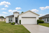 Charming modern home with a two-car garage, manicured lawn, and a sunny blue sky backdrop.
