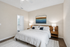 Bright and elegant bedroom with modern decor, featuring a plush bed, stylish artwork, and soft lighting, creating a serene atmosphere.