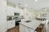 Modern open-concept kitchen with granite countertops, sleek white cabinets, and inviting living space in a stylish apartment.