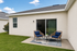 Charming patio with cozy wicker chairs and a small table, perfect for outdoor relaxation amidst a lush green lawn.