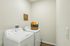 Modern laundry room featuring a sleek washer and dryer set with a decorative basket on top, set against a neutral wall for a stylish touch.