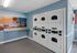 Modern laundry room equipped with stacked washers and dryers, complemented by a vibrant ocean-themed mural for a serene atmosphere.