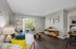 Charming living room with modern decor, featuring a cozy sofa, stylish floor lamp, and a view of a lush garden through sliding glass doors.