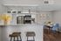 Modern kitchen with stainless steel appliances, granite countertops, and a chic breakfast bar adjacent to a stylish dining area with blue chairs.
