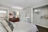 Elegant bedroom with cozy bed, modern dresser, ensuite bathroom, and open closet in a stylish apartment.