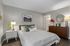 Inviting bedroom with modern decor, featuring a cozy bed, elegant dresser, and warm lighting for perfect relaxation.