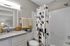 Chic and modern bathroom with a sleek granite countertop, elegant geometric shower curtain, and stylish decorative accents.