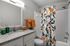 Charming bathroom featuring a modern granite countertop, vibrant floral shower curtain, and warm orange accents for a cozy touch.