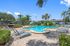 Inviting outdoor pool area with elegant loungers, surrounded by lush greenery and palm trees, perfect for relaxation.