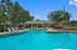 Luxurious outdoor pool with sleek sun loungers and lush green surroundings, perfect for relaxation.