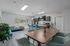 Modern communal kitchen and dining area featuring sleek cabinetry, a cozy seating nook, and vibrant greenery with ample natural light.