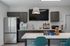Contemporary kitchen with sleek dark cabinetry, stainless steel fridge, modern coffee machine, and inviting bar seating.