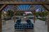 Charming outdoor lounge with cozy seating under a wooden pergola, perfect for evening relaxation.