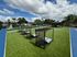 Vibrant outdoor recreational area featuring modern cabanas, lush green lawn, and a soccer goal under a clear blue sky.