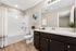 Elegant bathroom with sleek dark wood cabinetry, a pristine white bathtub, and chic decor for a modern and refreshing touch.
