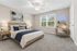 Inviting bedroom featuring a cozy bed with beach-themed decor, modern desk with 'Good Vibes' neon sign, and natural light from large window.