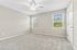 Bright and airy empty room featuring soft carpet, large windows with scenic views, and a modern ceiling fan.