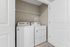Bright laundry room with modern washer and dryer, featuring ample shelving space for organization.