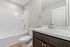 Bright and modern bathroom featuring a sleek bathtub, elegant vanity with a marble countertop, and stylish fixtures.