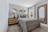 Charming bedroom with cozy decor, featuring dinosaur-themed artwork, a plush bed, stylish lamps, and a large wall mirror, perfect for a comfortable retreat.