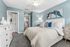 Inviting bedroom with plush carpet, elegant dresser, and soothing blue walls creating a serene retreat.