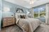 Inviting bedroom in soft blue tones with elegant decor, plush bedding, and large window offering serene garden view.