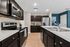 Modern kitchen with sleek dark cabinetry, stainless steel appliances, and a spacious island with dual sinks.