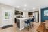 Modern apartment kitchen with sleek dark cabinetry, stainless steel appliances, and a spacious island with chic blue bar stools.