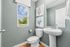 Bright and modern bathroom featuring a pedestal sink and elegant decor, with ample natural light from a large window.