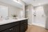 Elegant bathroom with dual sinks, modern fixtures, and a spacious walk-in shower accented by warm wood flooring and tasteful decor.