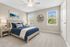 Bright and cozy bedroom with elegant decor, featuring a plush blue bed, modern artwork, and large windows offering serene outdoor views.