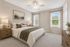 Elegant bedroom with neutral decor, featuring a plush bed, wooden nightstands, and natural light streaming through large windows.