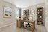 Elegant home office with neutral tones features a modern wooden desk, plush chair, and bright natural light. Stylish bookshelves and coastal artwork create an inspiring workspace.