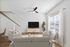 Inviting living room with modern light decor, featuring cozy sofas, a stylish TV setup, and abundant natural light from large windows.