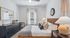 Inviting bedroom with cozy decor, featuring a stylish black dresser, comfortable bed with plush pillows, and ample natural light from a large window.