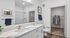 Elegant bathroom with dual sinks, modern fixtures, and a spacious walk-in closet, featuring stylish tile accents and bright lighting.