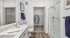 Elegant bathroom with modern double sink vanity, glass-enclosed shower, and adjacent walk-in closet featuring chic white and blue decor.
