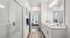 Elegant bathroom with a luxurious glass shower, double vanity, and modern fixtures, leading into a bright bedroom.