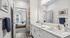 Bright and modern bathroom with dual sinks and sleek countertop, opening to a cozy bedroom with stylish decor and soft lighting.