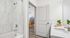 Bright, modern bathroom featuring a sleek marble-tiled shower and stylish vanity, with a glimpse into a cozy living area.
