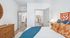 Inviting bedroom with vibrant orange headboard, cozy blue and orange pillows, and a spacious walk-in closet, offering perfect comfort and style.