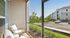 Charming apartment patio with cozy seating, overlooking a lush green landscape and modern residential buildings, perfect for relaxation.