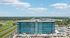 Stunning aerial view of a modern glass-fronted building with lush green surroundings and a serene lake in the background, perfect for luxurious living.