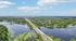 Scenic aerial view of a serene waterfront with lush greenery and a picturesque bridge, perfect for tranquil living.