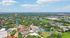 Vibrant aerial view of a bustling theme park with colorful rides, lush greenery, and expansive surroundings under a clear blue sky.
