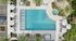 Luxurious aerial view of a pristine swimming pool with surrounding sun loungers and elegant white umbrellas, set amidst lush greenery and palm trees.