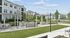 Inviting outdoor area with modern grills and stylish seating amidst lush greenery in a serene apartment complex setting.