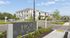 Modern apartment complex with elegant architecture and lush landscaping at Hom at Riverhills, showcasing a serene setting under clear blue skies.