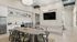 Modern open-concept living area showcasing a stylish kitchen with sleek white cabinetry, a cozy dining table, and elegant lighting fixtures, perfect for entertaining.