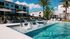 Luxurious apartment complex with a stunning outdoor pool and relaxing sun loungers surrounded by lush greenery.